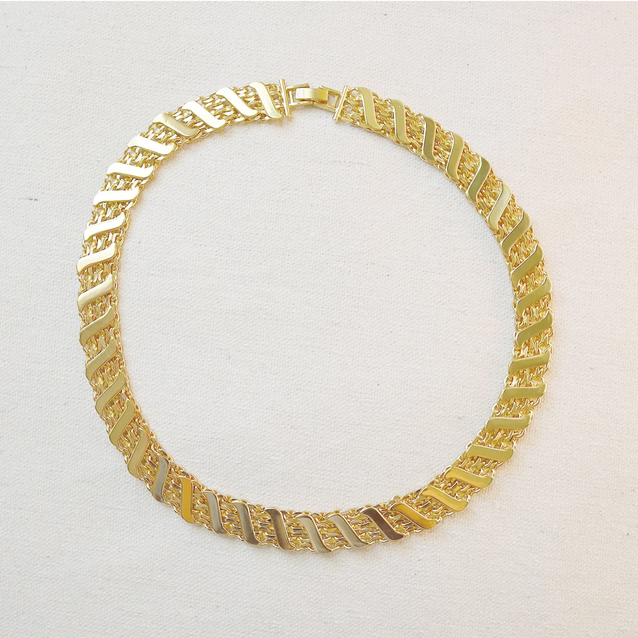 A gold statement necklace with a twisted rope detail. 