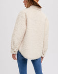 On a white background is a model wearing a boucle shirt jacket with buttons and front pockets.