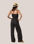 A black jumpsuit with a smocked bust / midsection area and tie spaghetti shoulder straps.