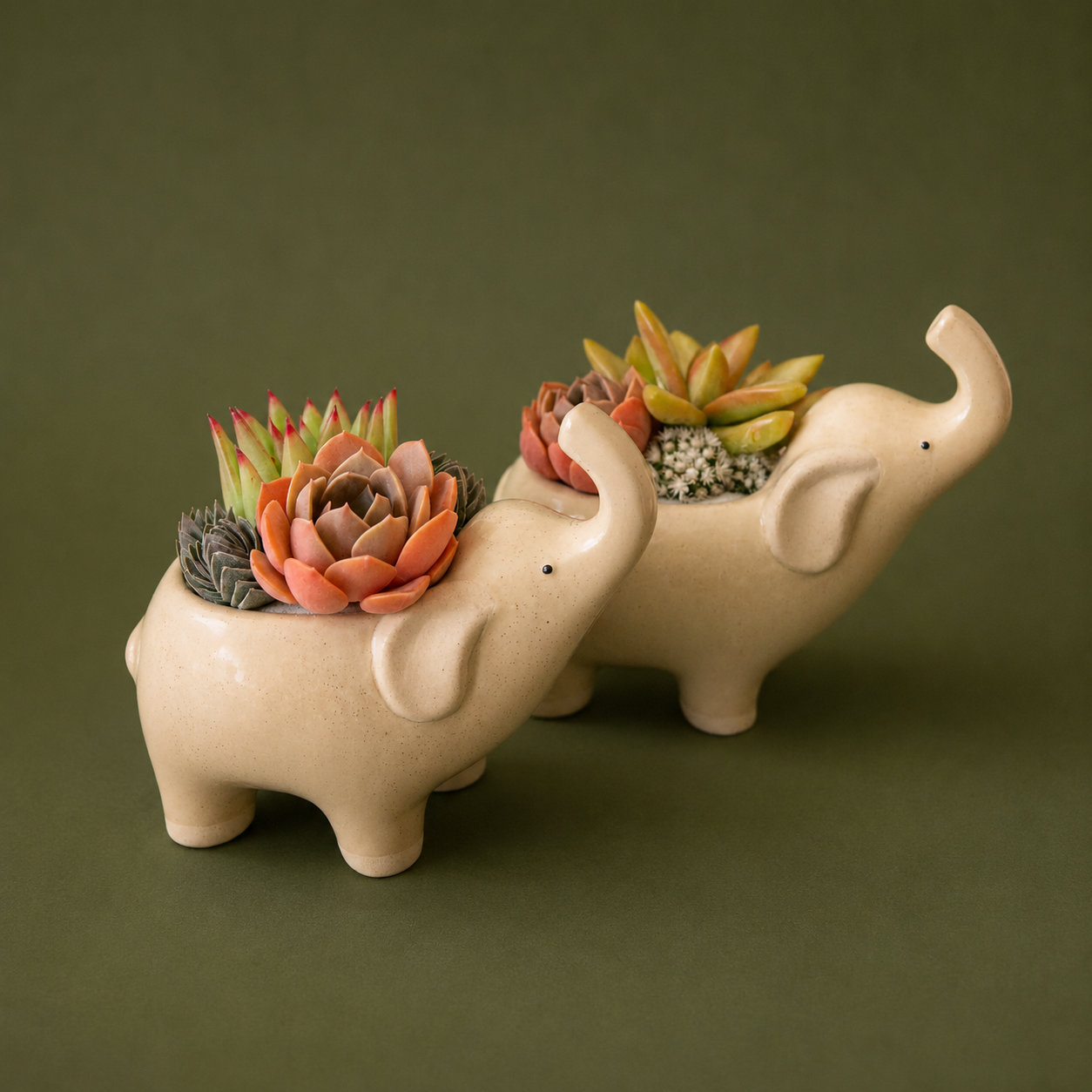 Two ceramic elephant with their nose in the air.  The ceramic is a tan color with speckles.