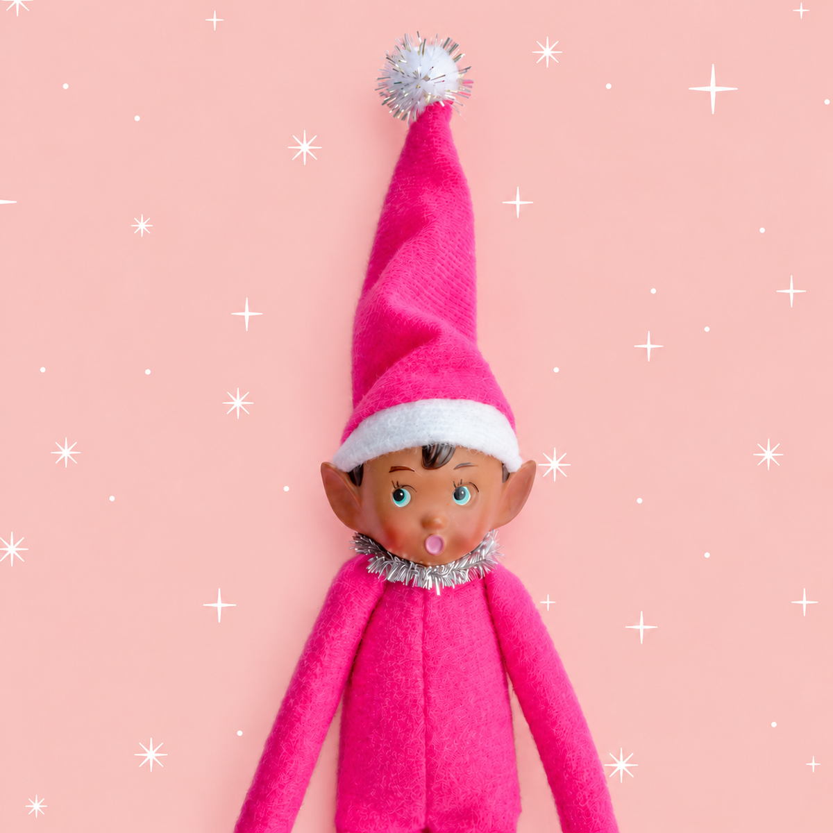 hot pink elf ornament on a soft pink background with white stars.