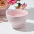A ceramic pedestal bowls / vase that is pink. 
