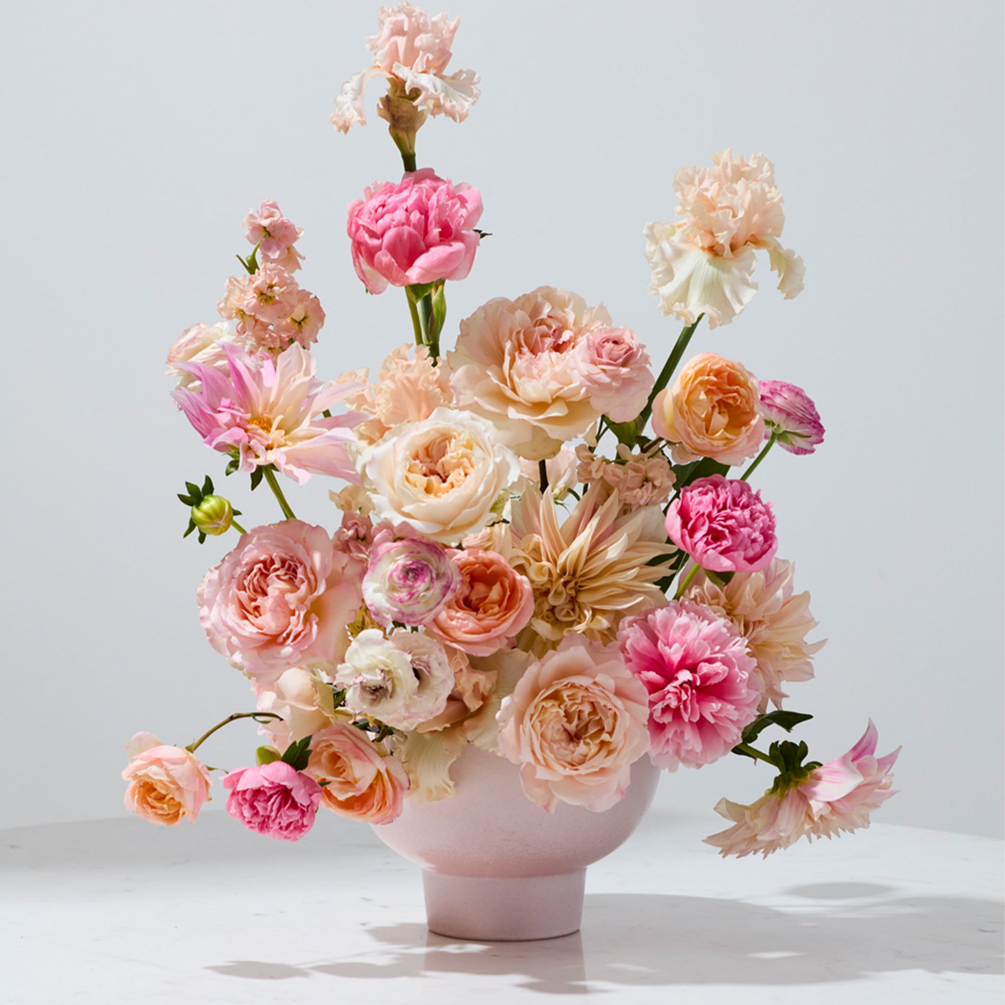 A ceramic pedestal bowls / vase that is pink. 