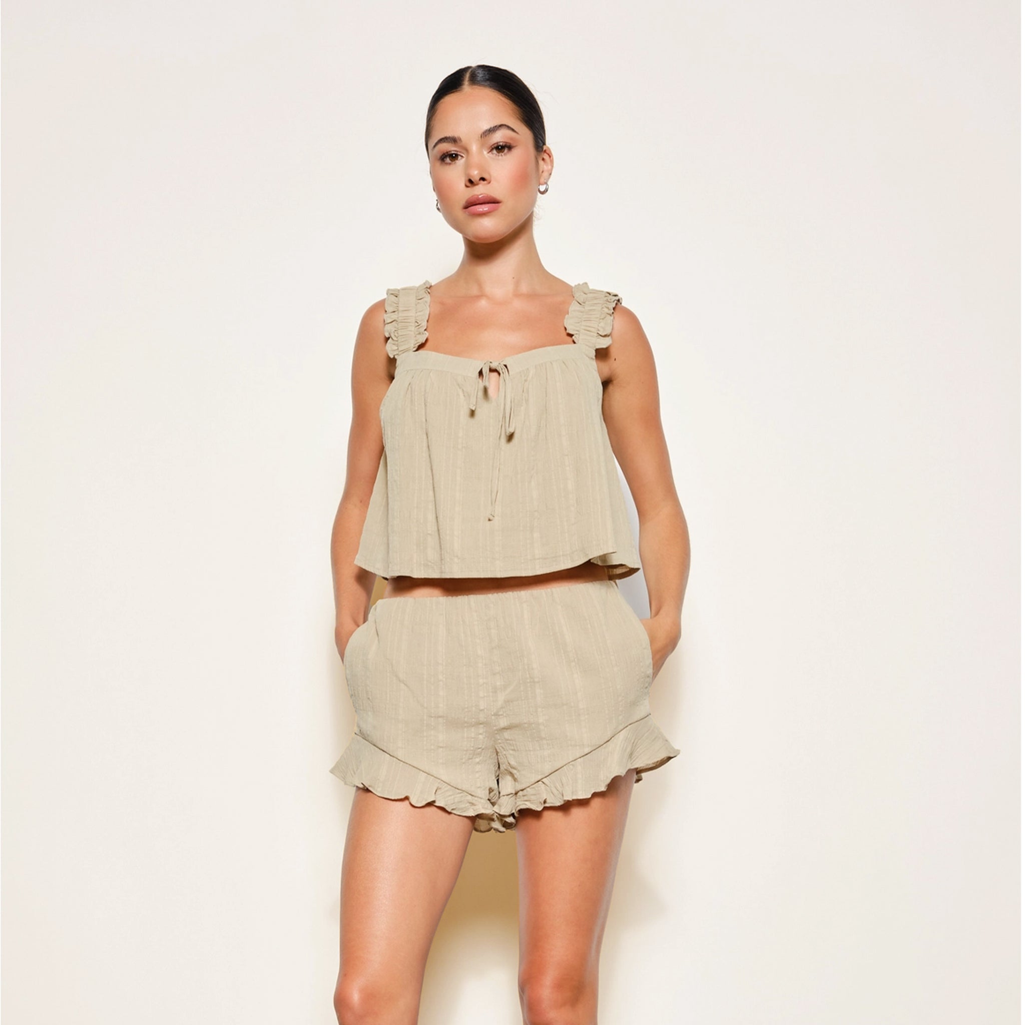 A light olive green flowy tank top with frilly shoulder straps. 