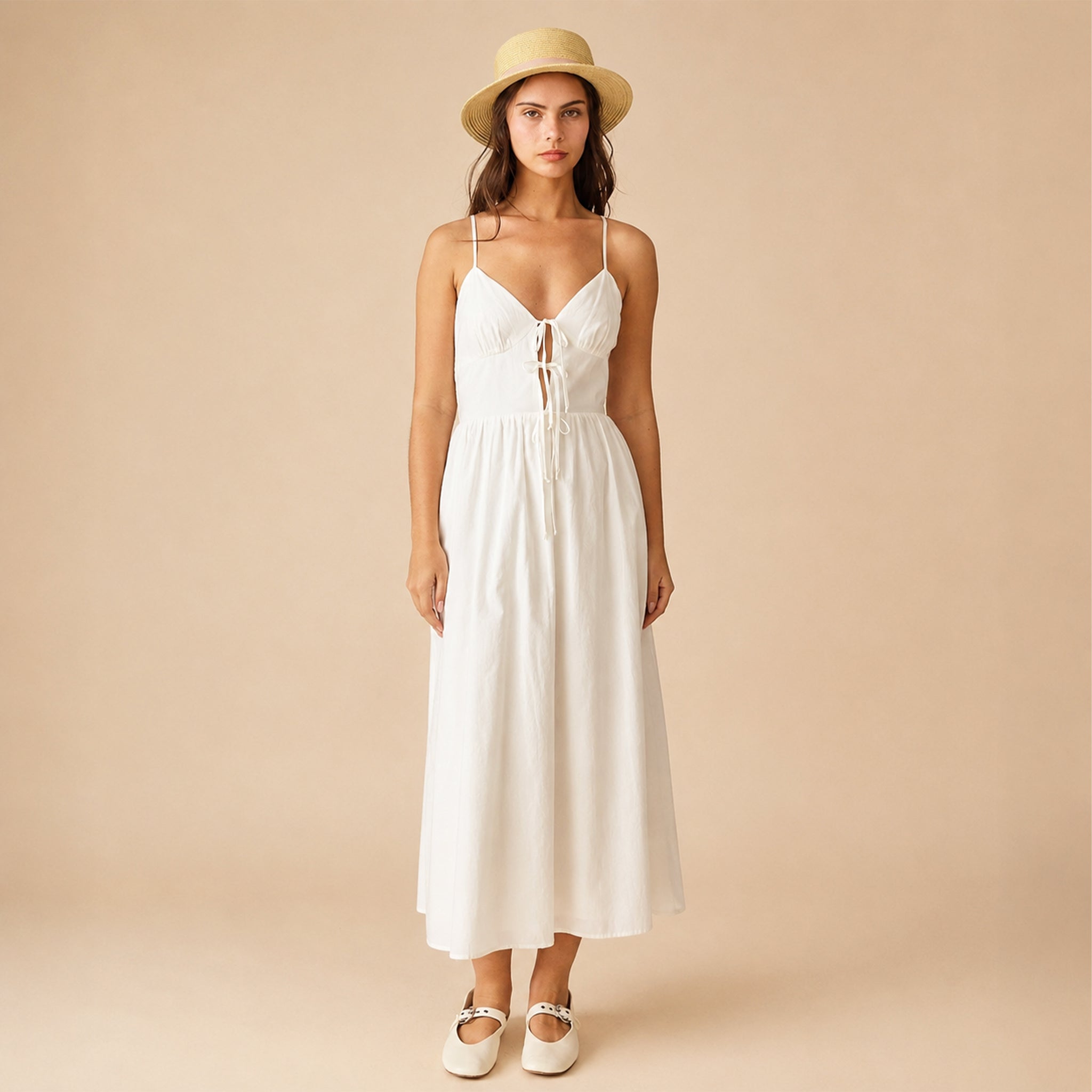 Woman wearing a white dress and straw hat on a beige background