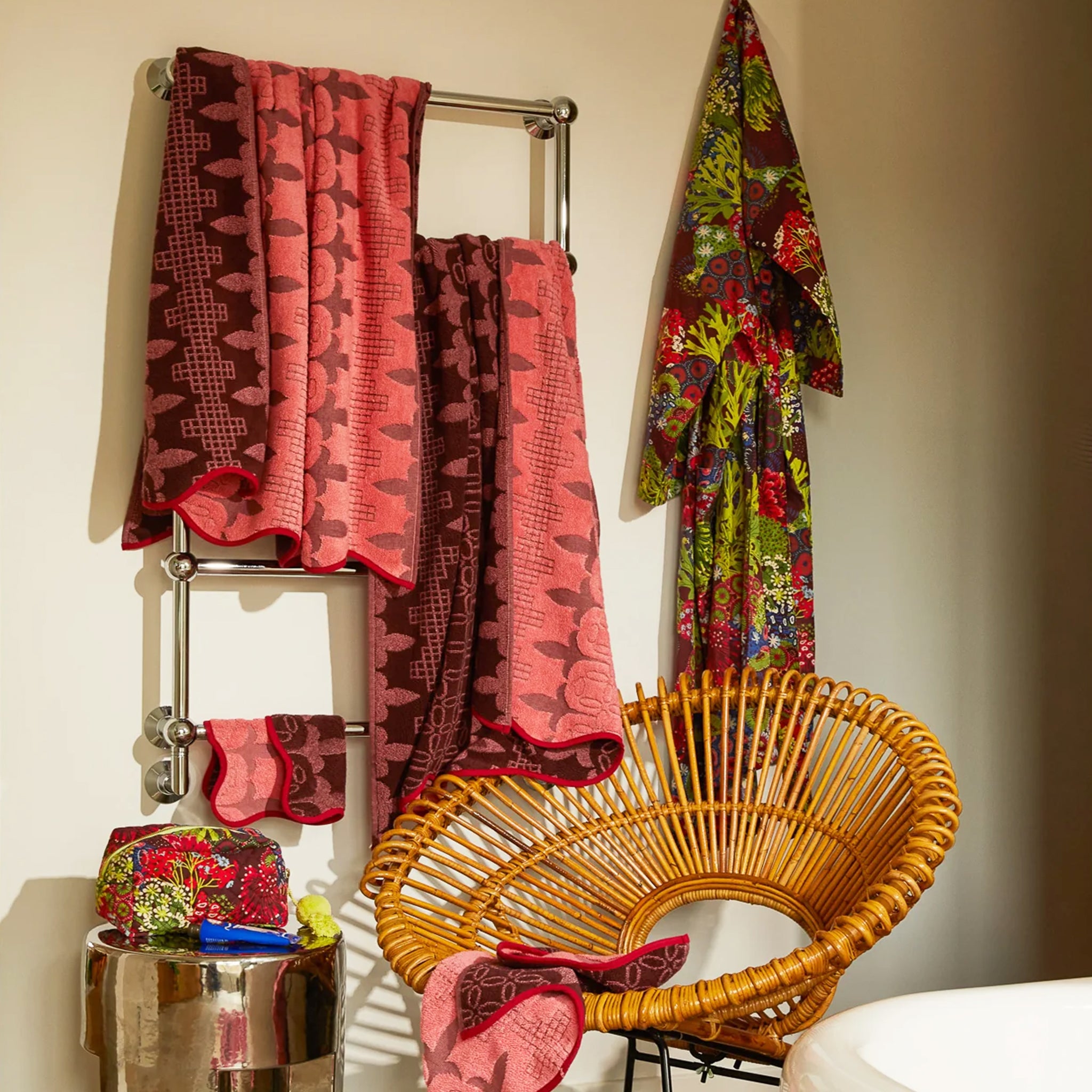 A pink and red piping edge bath towel with a wavy end on both sides. 