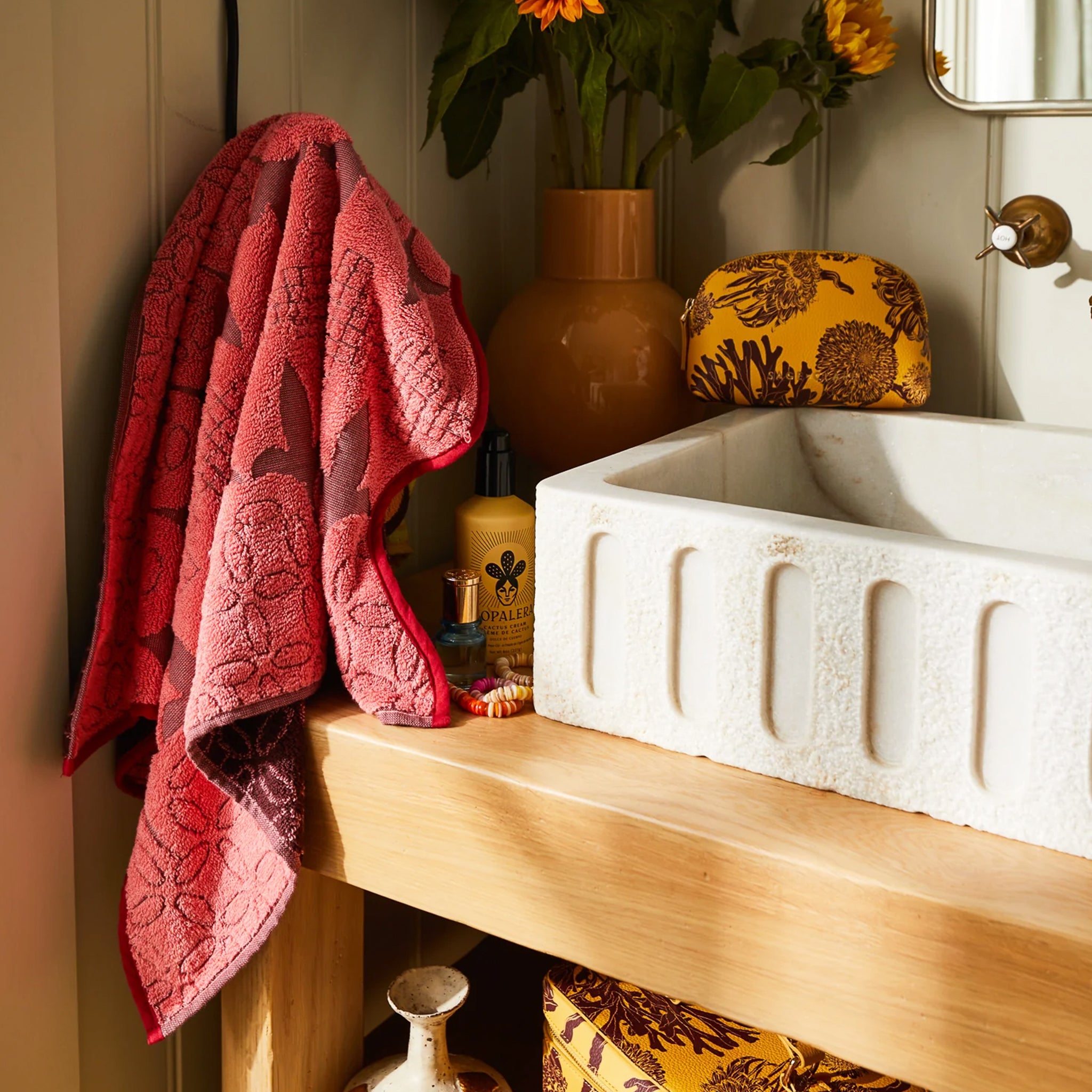 A pink and red piping edge hand towel with a wavy end on both sides. 