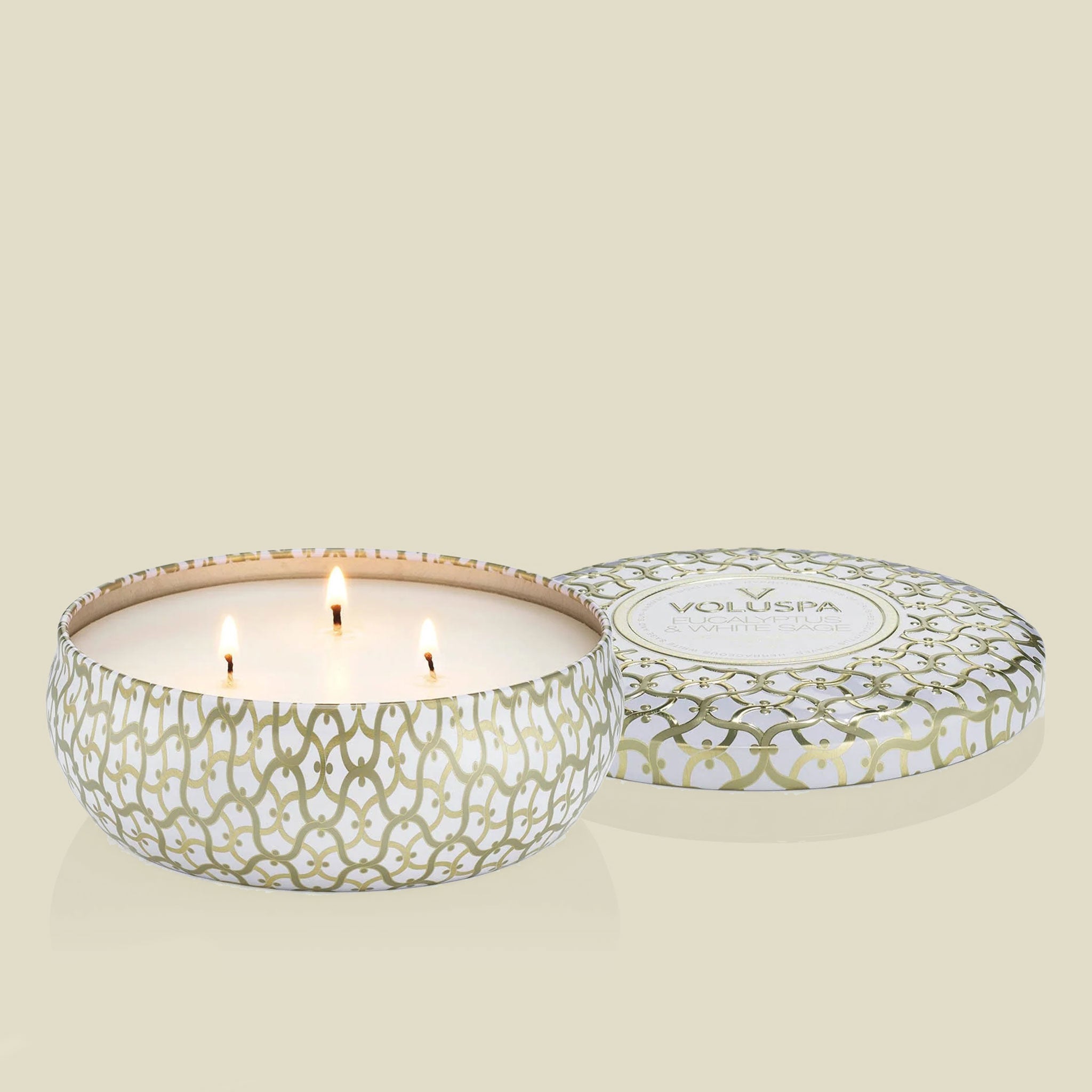 A round three wick candle in a white and gold cross design tin.
