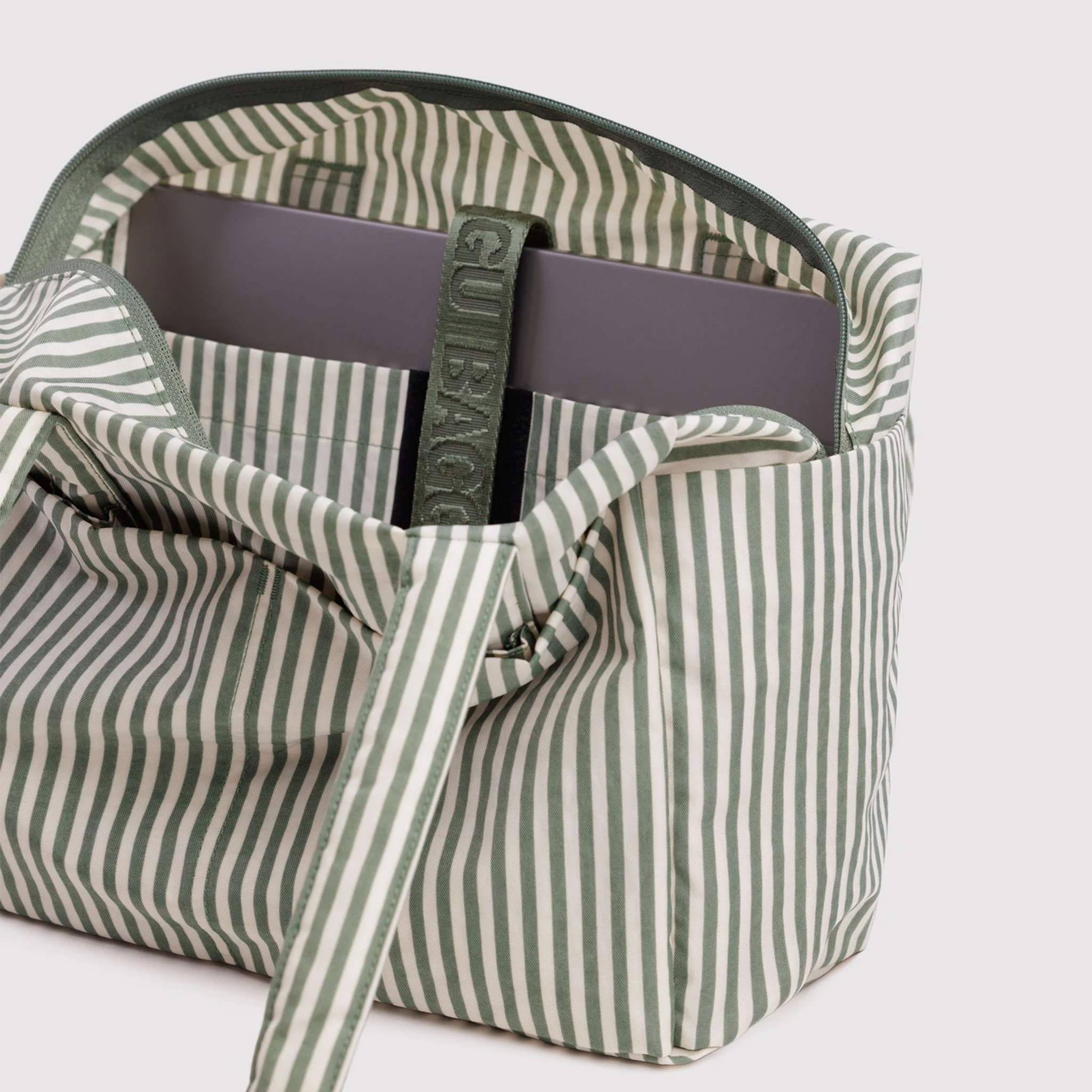 sage colored striped bag interior with laptop showing.