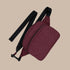 A mahogany, burgundy colored fanny pack with a black strap. 