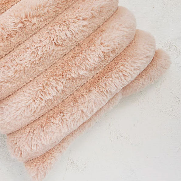 A light pink faux fur square pillow. 