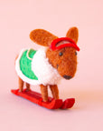 A brown dachshund shaped ornament on skis and wearing a green jacket. 