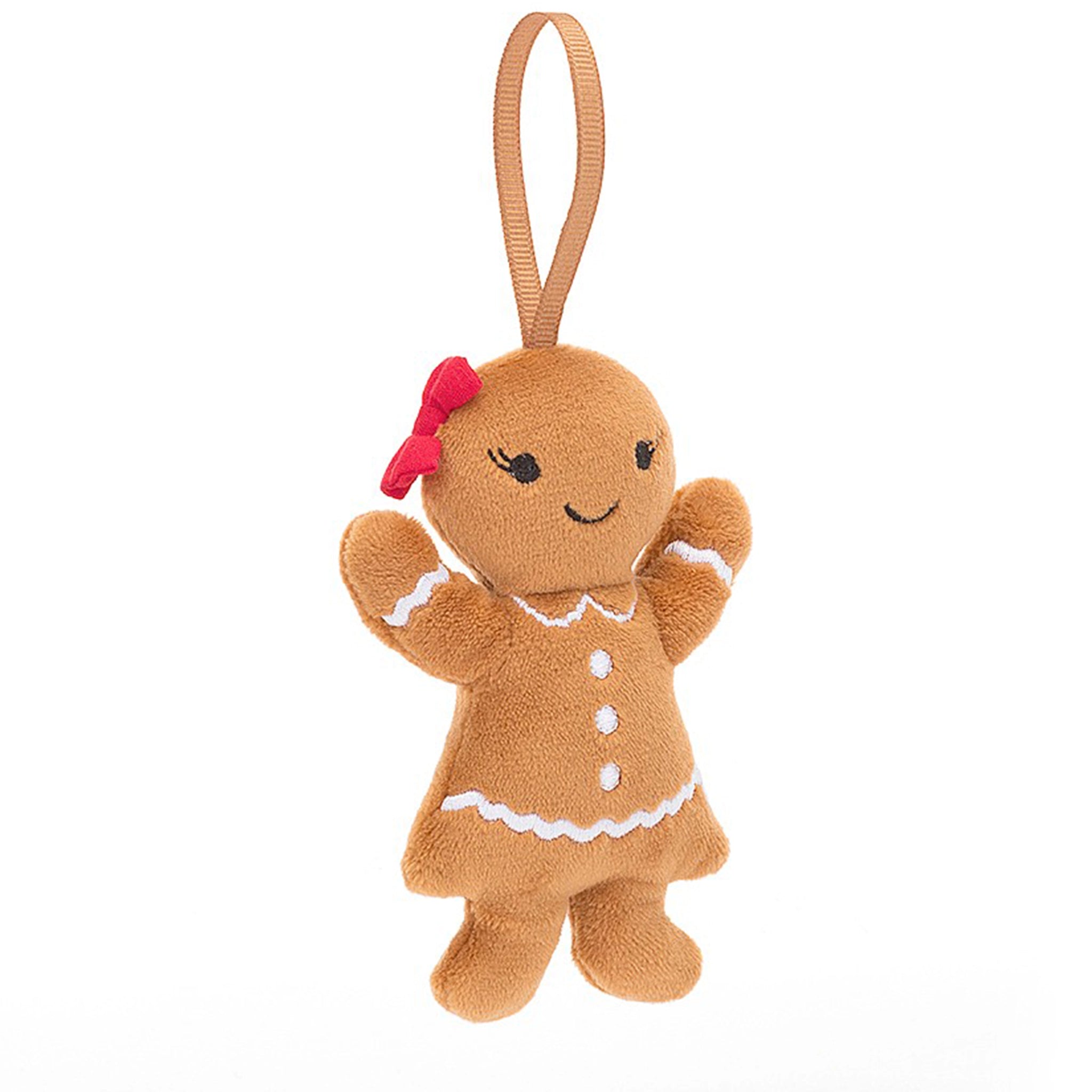 On a white background is a brown gingerbread shaped stuffed toy with a smiling face, white detailing and a red bow on her head. 