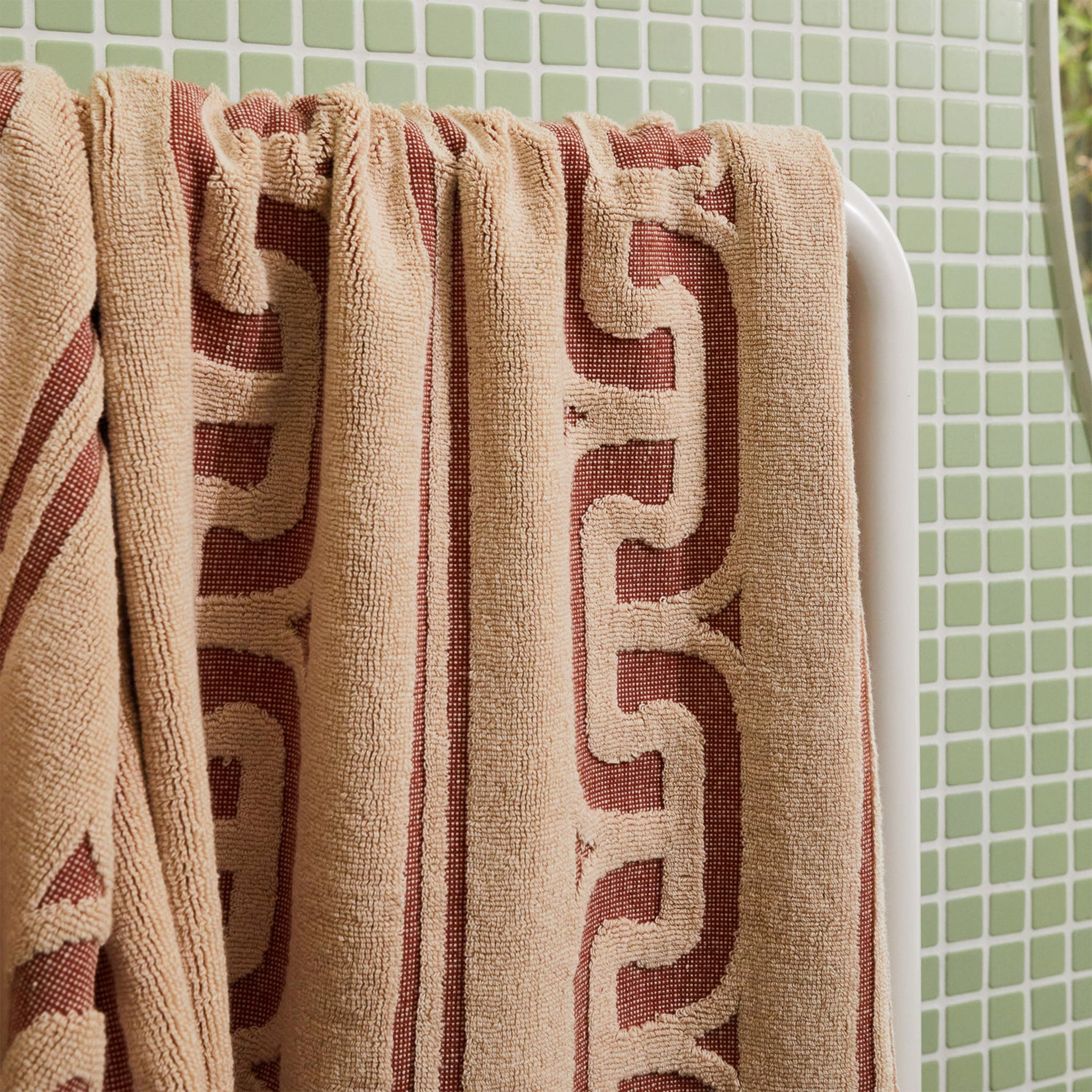 A brown and dark brown bath towel with a wavy design and fringe edge. 