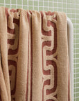 A brown and dark brown bath towel with a wavy design and fringe edge. 