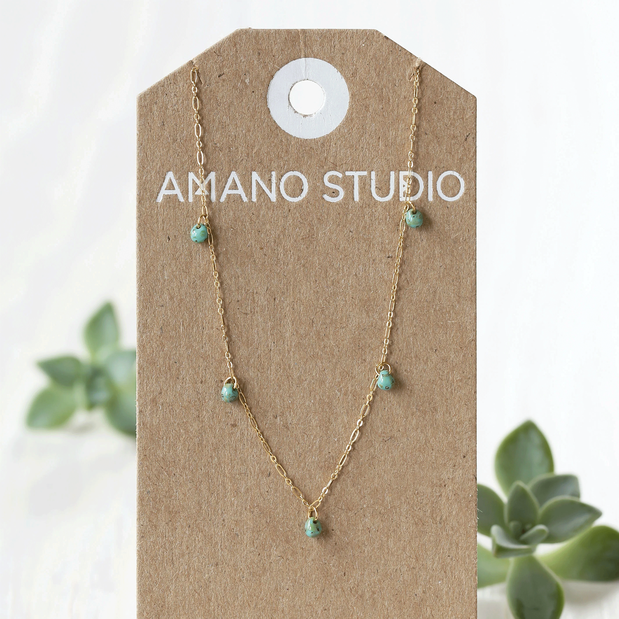 A gold dainty chain necklace with five turquoise beads spaced out along the chain. 