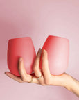 A pair of two pink and peachy silicone stemless wine glasses for on-the-go beverages.
