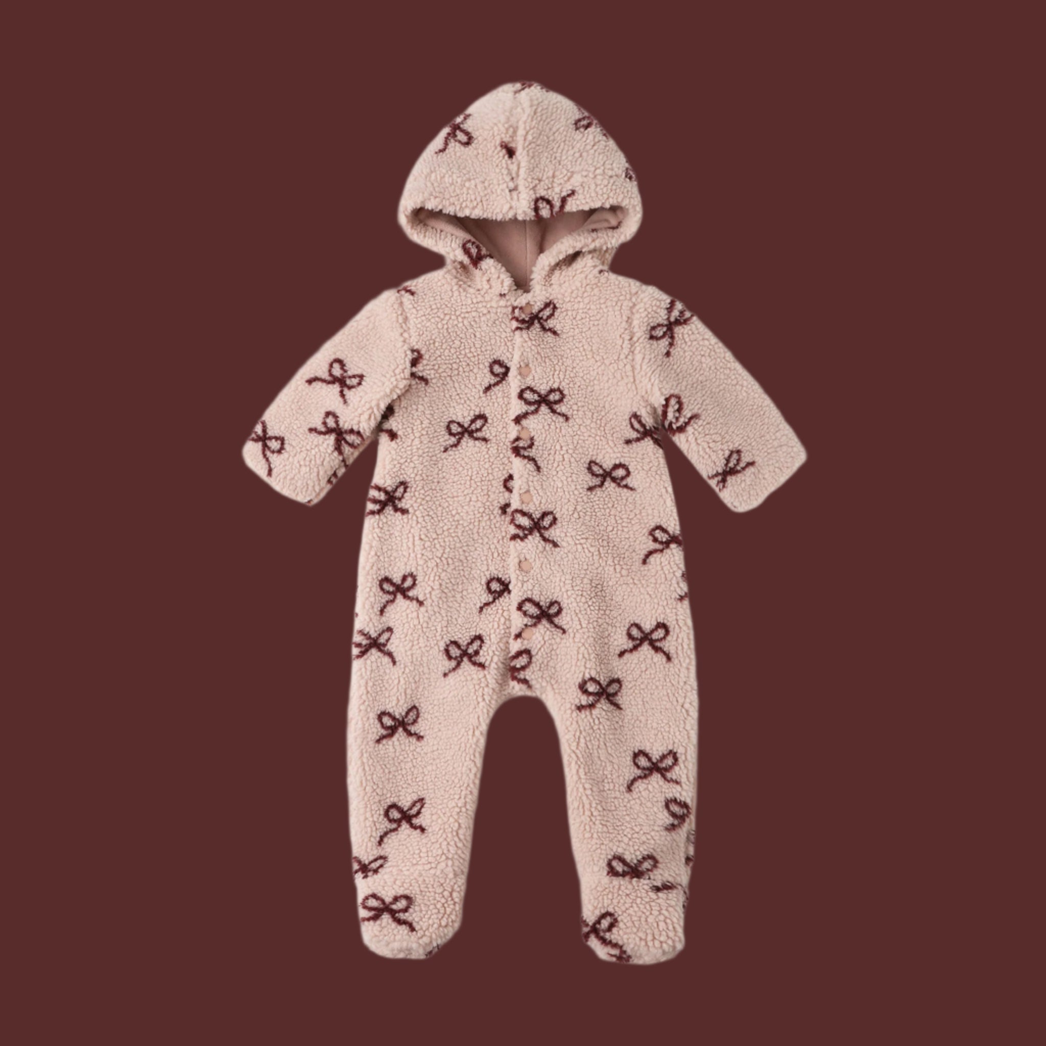 A beige fleece onesie with a hood and dark red bow patterns. 