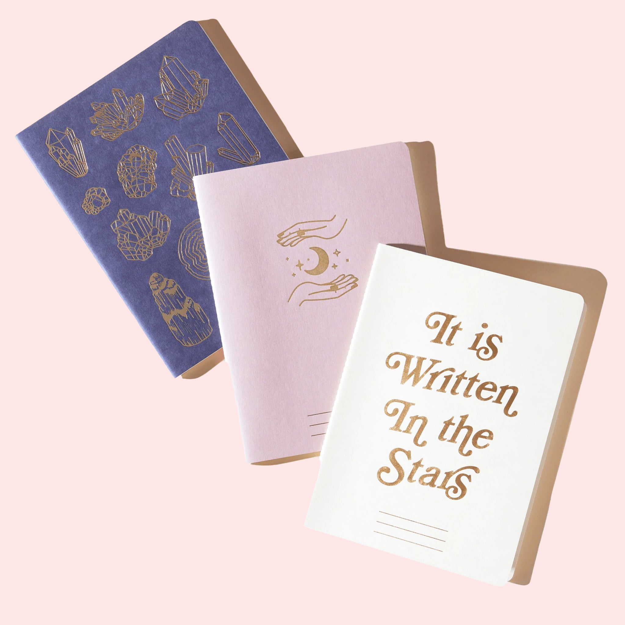 On a light pink background is three different notebooks, one blue/purple, one pink and the other ivory and reads, "It is Written In the Stars". 