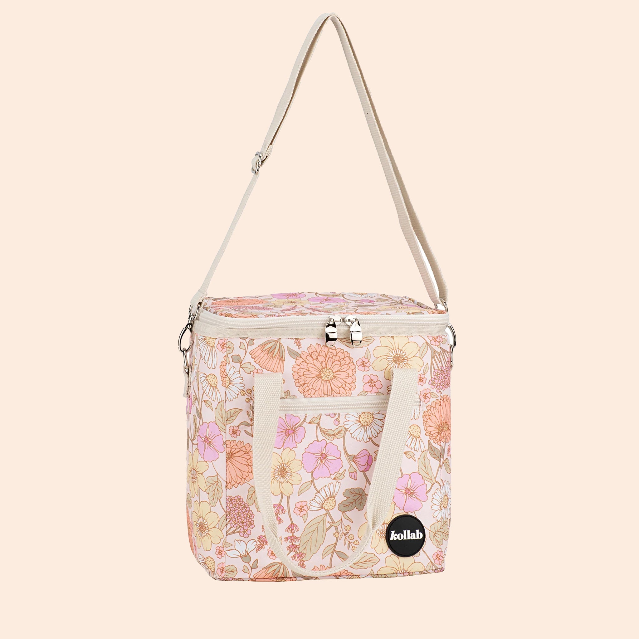 A pink and yellow muted floral printed cooler bag with a strap.