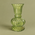 A  light green ribbed glass vase with a flared rim, a bulbous base, and a small pedestal foot, set against a solid beige background.