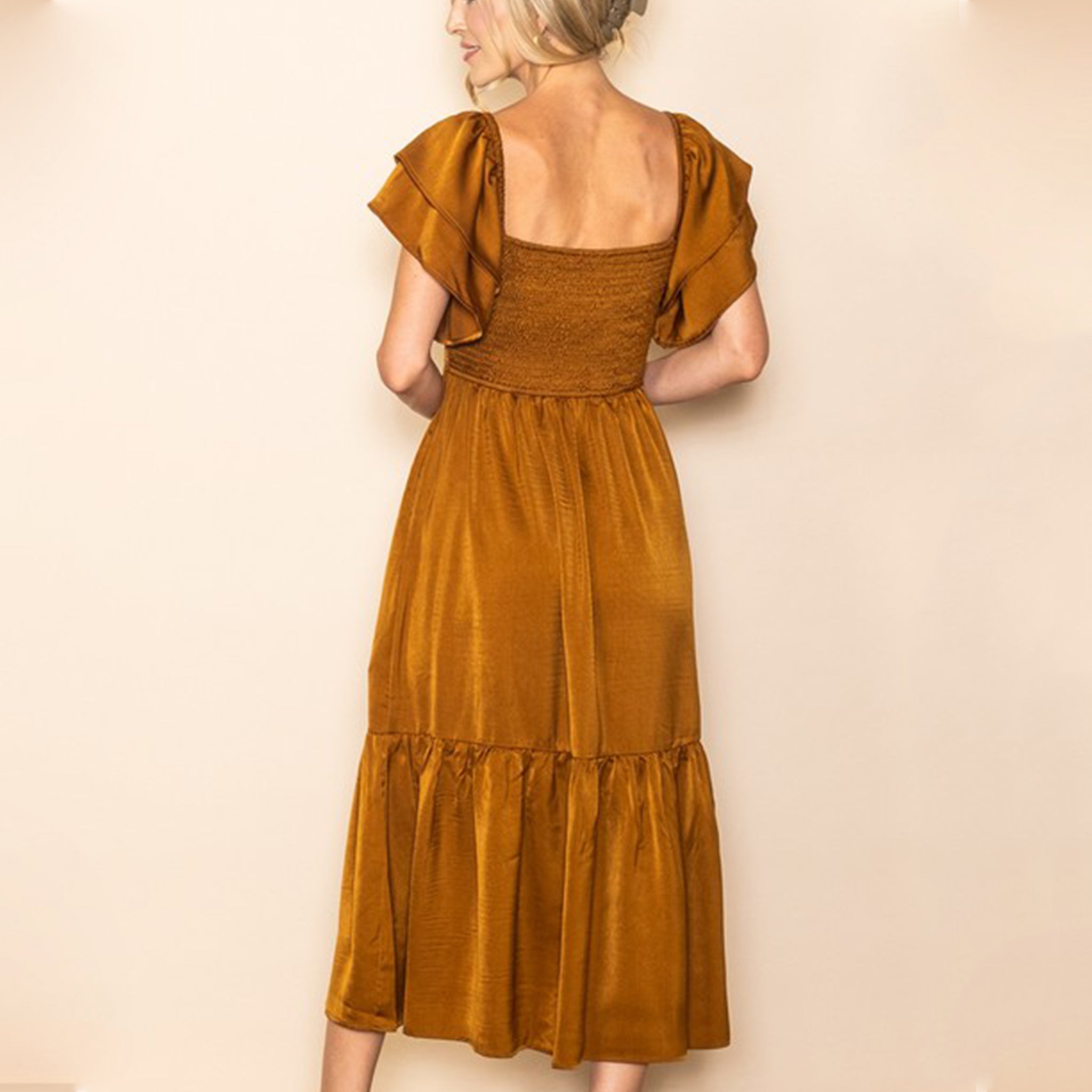 A copper satin dress with a smocked bodice, flutter sleeves and a tiered skirt bottom.