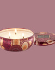A red and tan floral print metal tin with a three wick candle inside. 