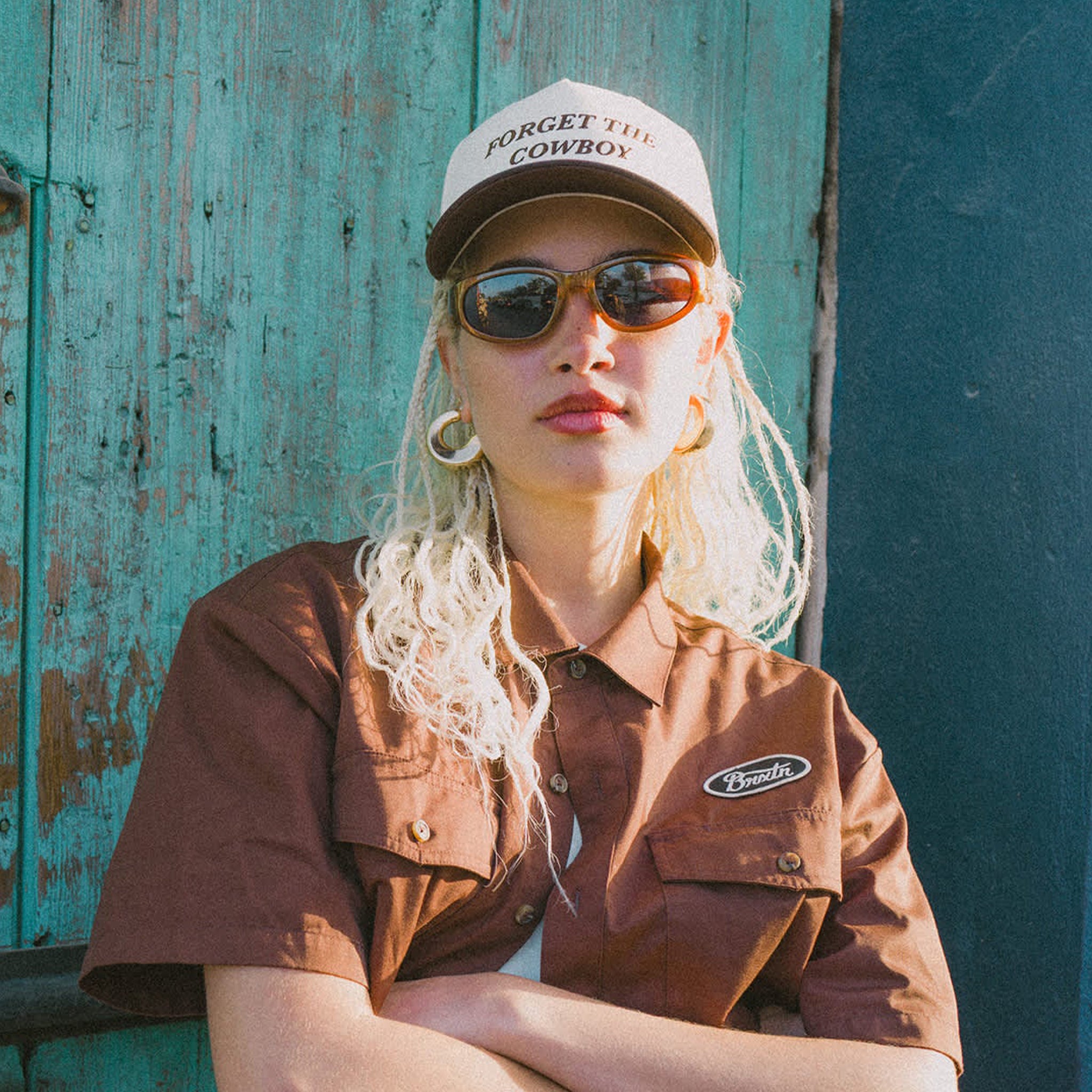 A white and brown two-toned snapback that reads, "Forget The Cowboy". 