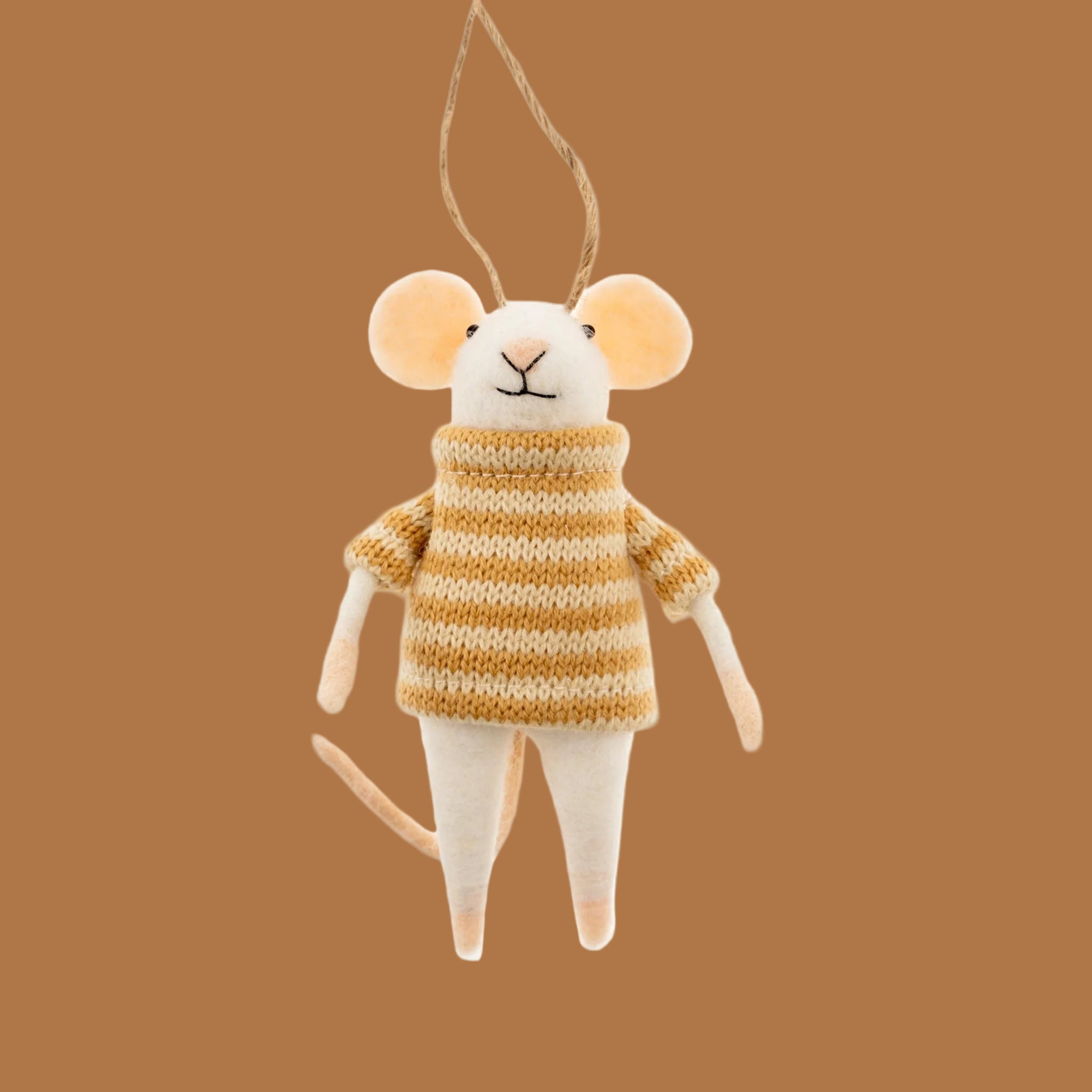 A white mouse shaped felt ornament wearing a yellow striped sweater on a nutmeg colored background.
