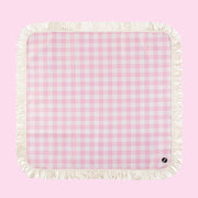 A pink and white checkered picnic blanket with a fringe edge. 