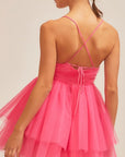 On a neutral background is a model wearing a hot pink tulle mini dress with a sweetheart neckline and thin straps.