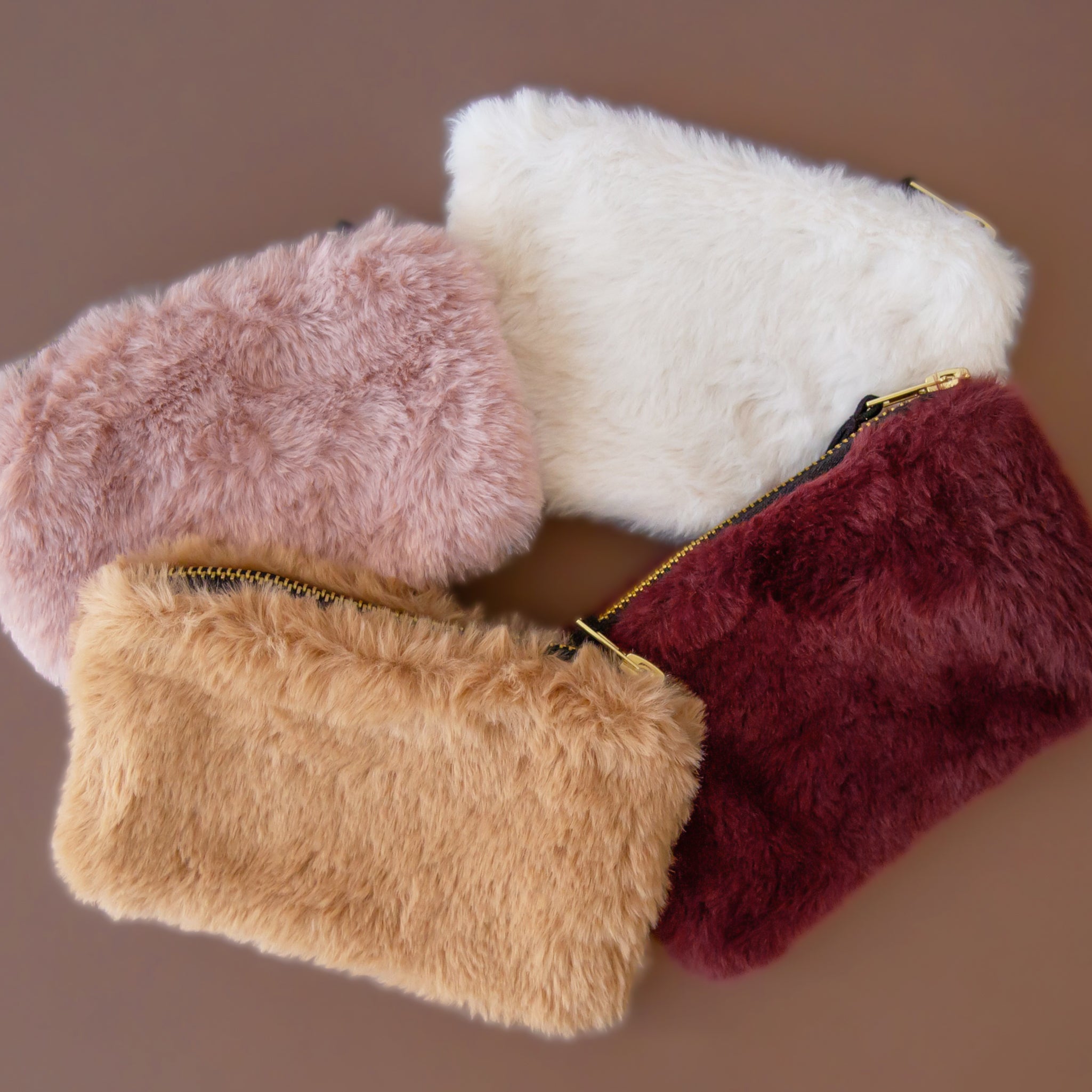 A faux fur pouch with a zipper in four different colors. 
