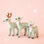 On a peachy background is three different sized mint green furry reindeer ornaments. 