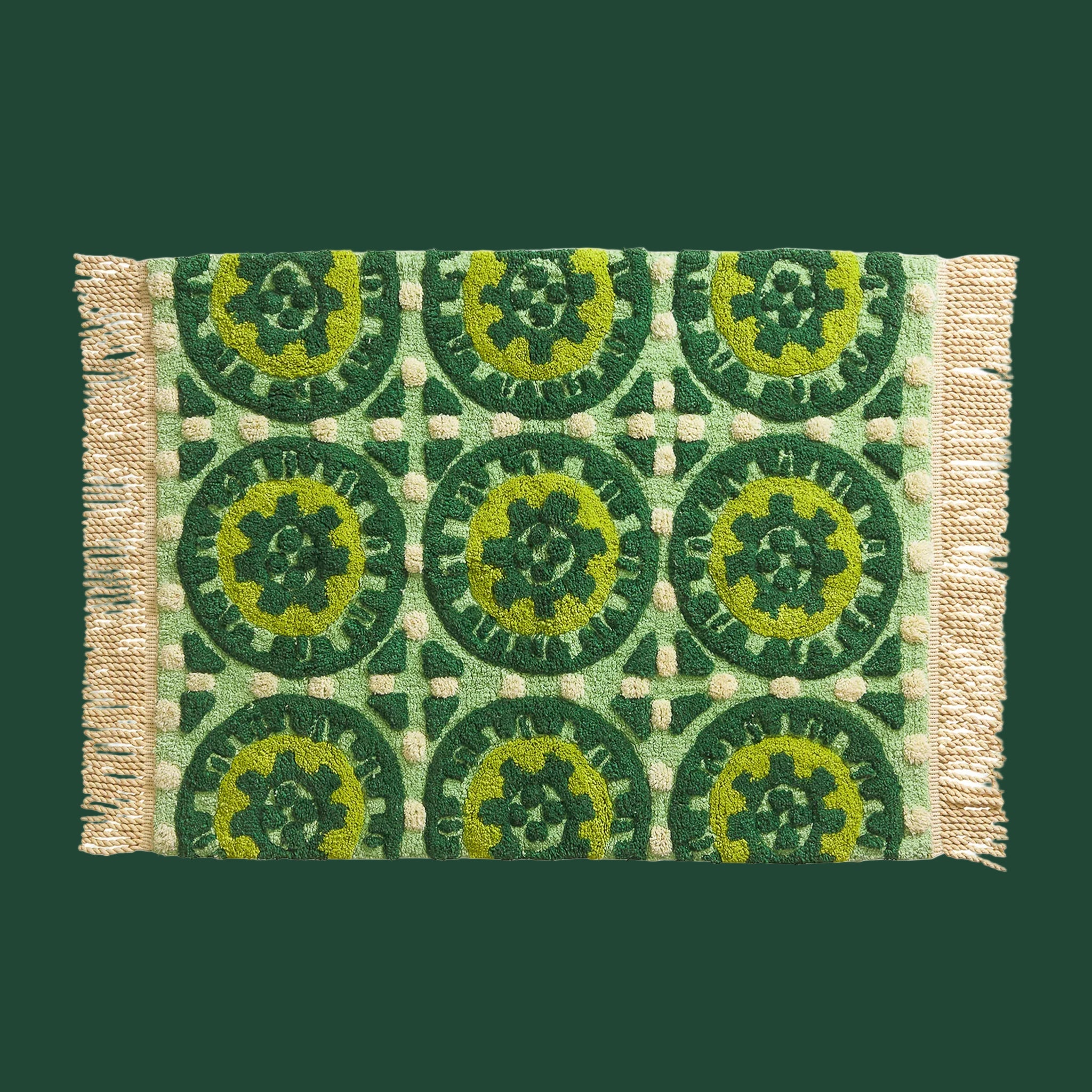 A green patterned bath mat with fringe edges. 