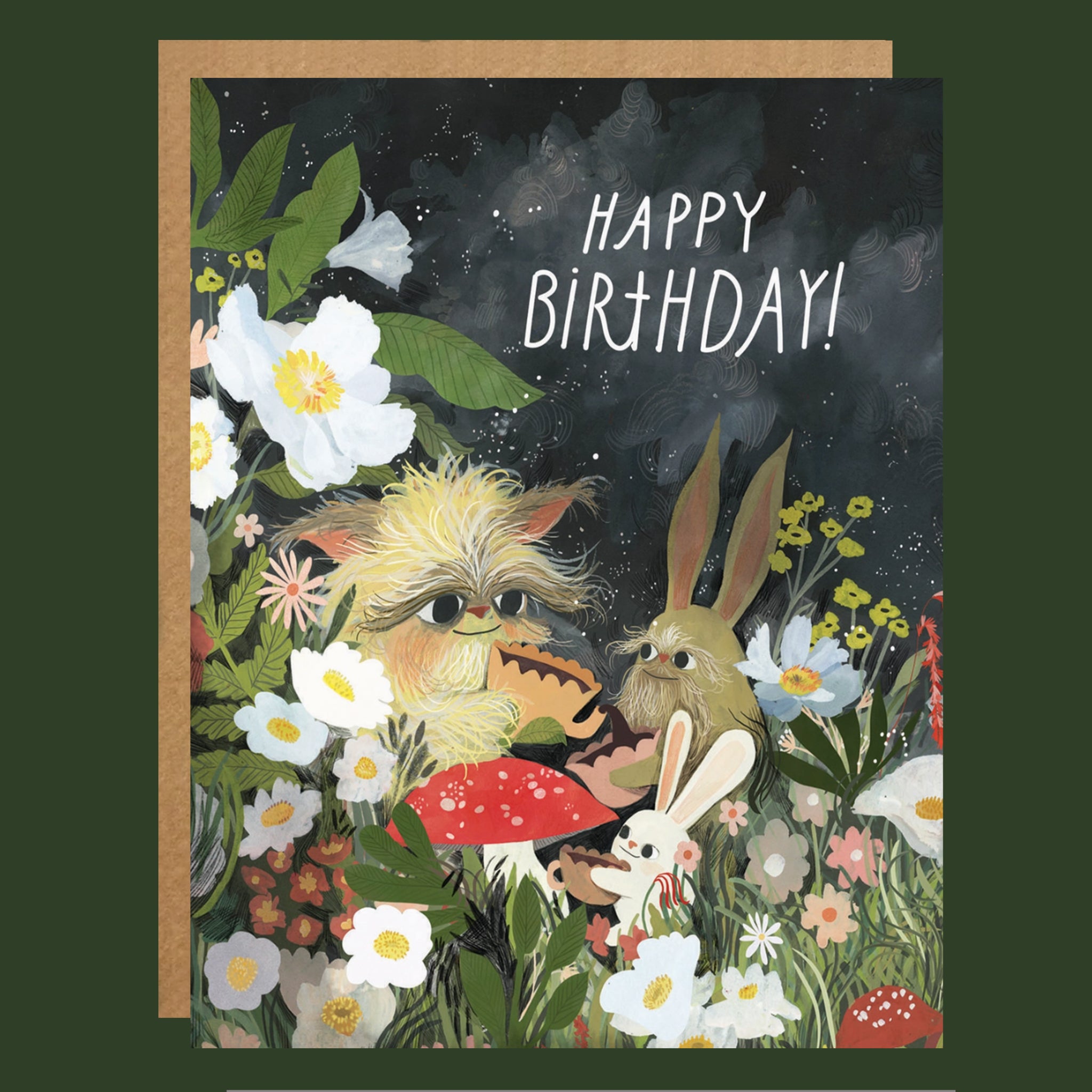 A square greeting card with a kraft envelope, featuring an illustrated woodland birthday scene with flowers, mushrooms, a fluffy creature, a rabbit, and the words “HAPPY BIRTHDAY!” on a dark night-sky background.