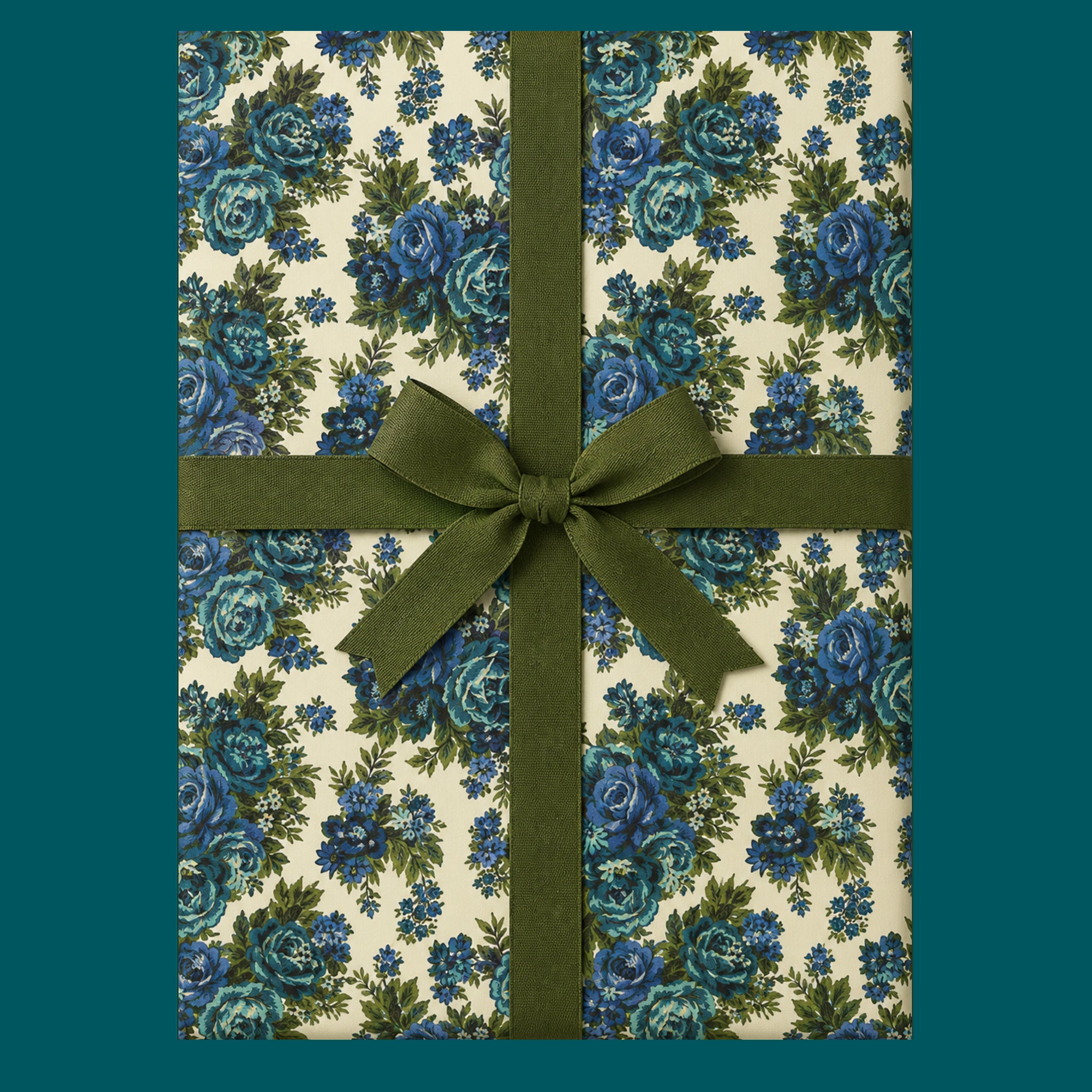A package wrapped in a vintage blue floral wrapping paper with a green ribbon.