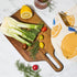 A wood cutting board / cheese board and a gold knife. 