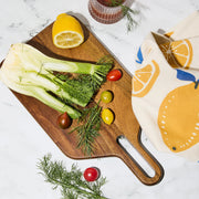 A wood cutting board / cheese board and a gold knife. 