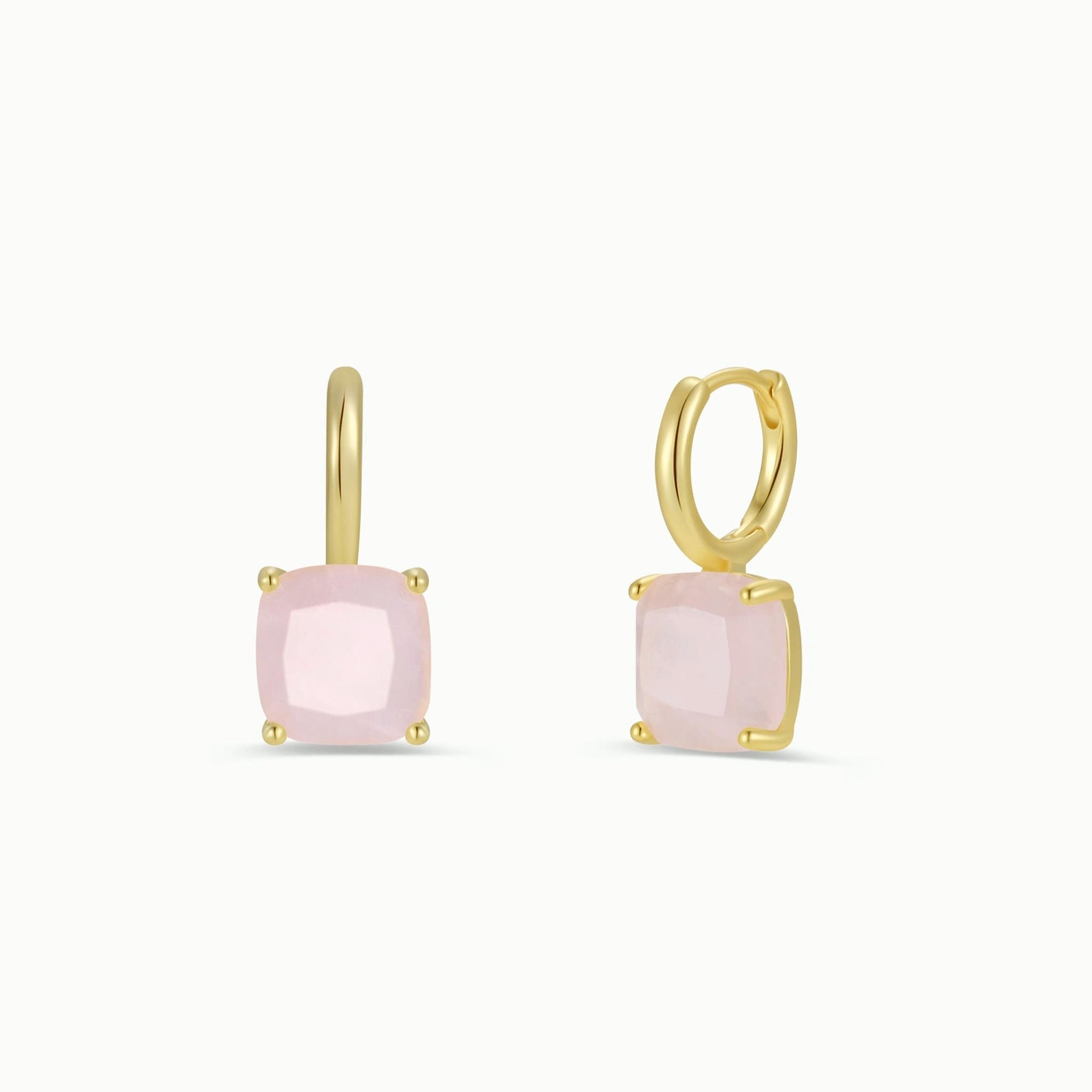 A gold pair of hoop earrings with light pink rose quartz stones. underneath. 