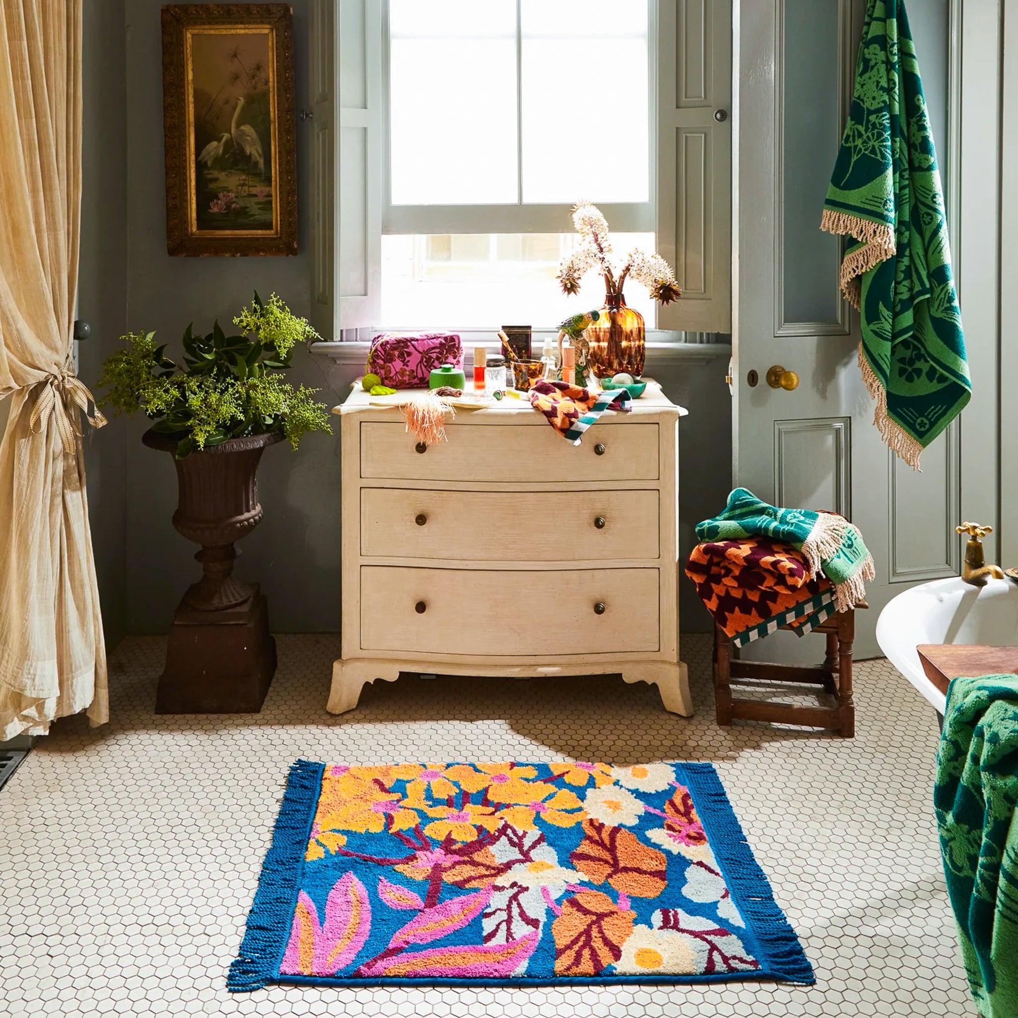 Blue bath mat with blue fringe, with orange, pink and white flowers.