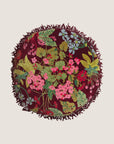 A maroon and multi colored floral round pillow with a fringe edge. 