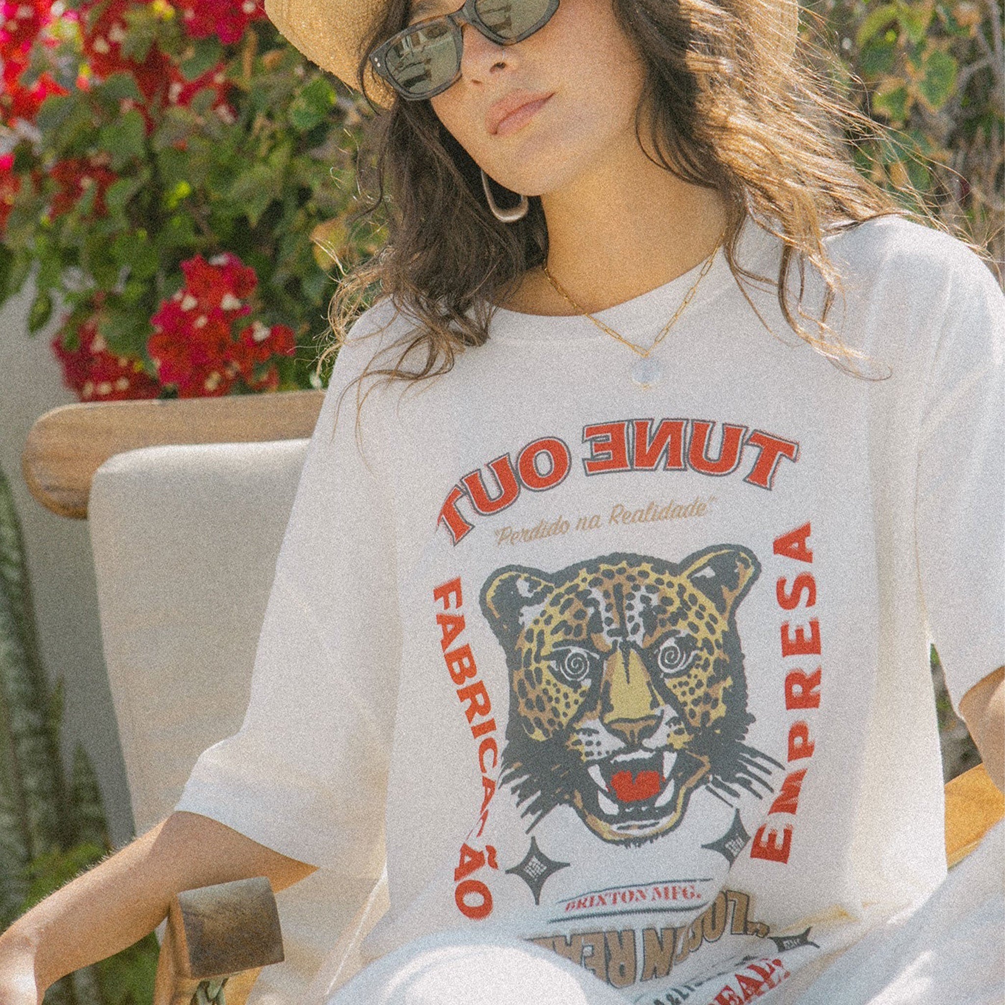 A white oversized BF fit tshirt with a tiger graphic that reads, "Tune Out Fabricacao Empresa Lost In Reality". 