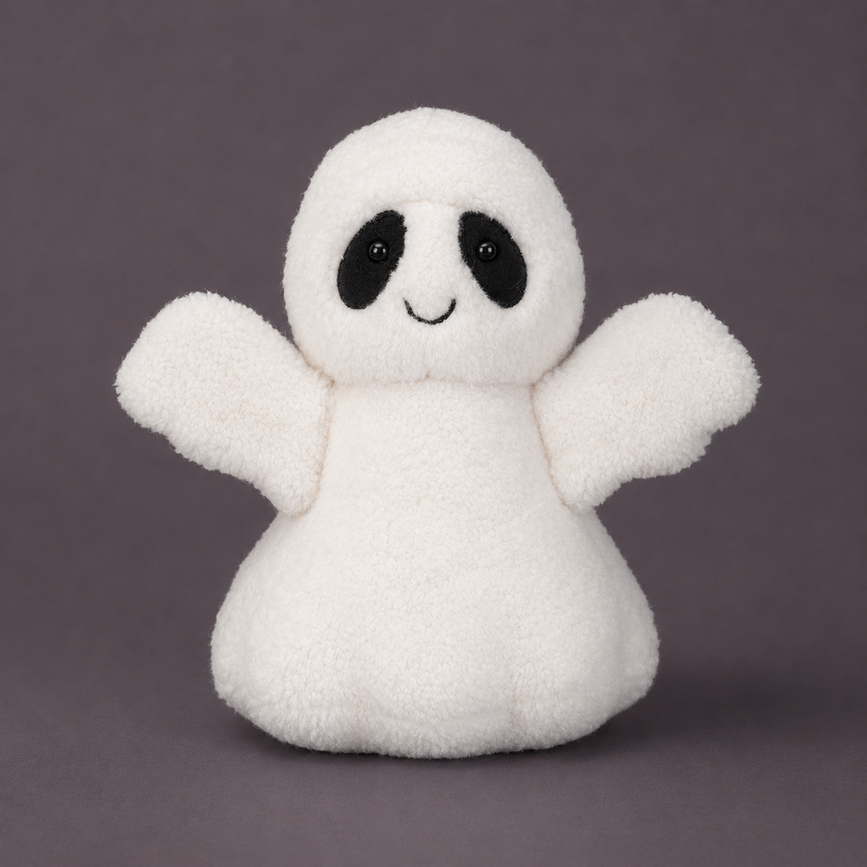 A white plush ghost toy with black embroidered eyes and a small smile, standing against a solid dark gray background.