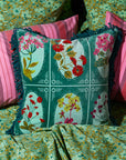 A green square pillow with red, yellow and pink floral print.