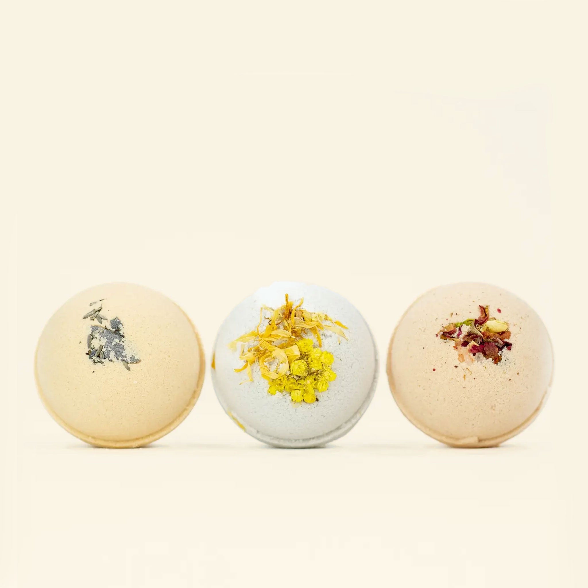 On a neutral background is three different scents of bath bombs.