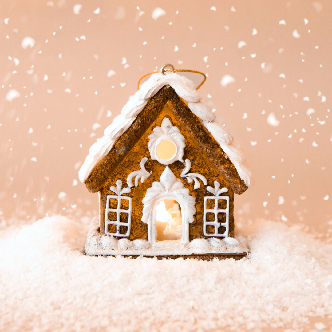 A gingerbread house shaped ornament with white pipping details and lights coming from the inside. 