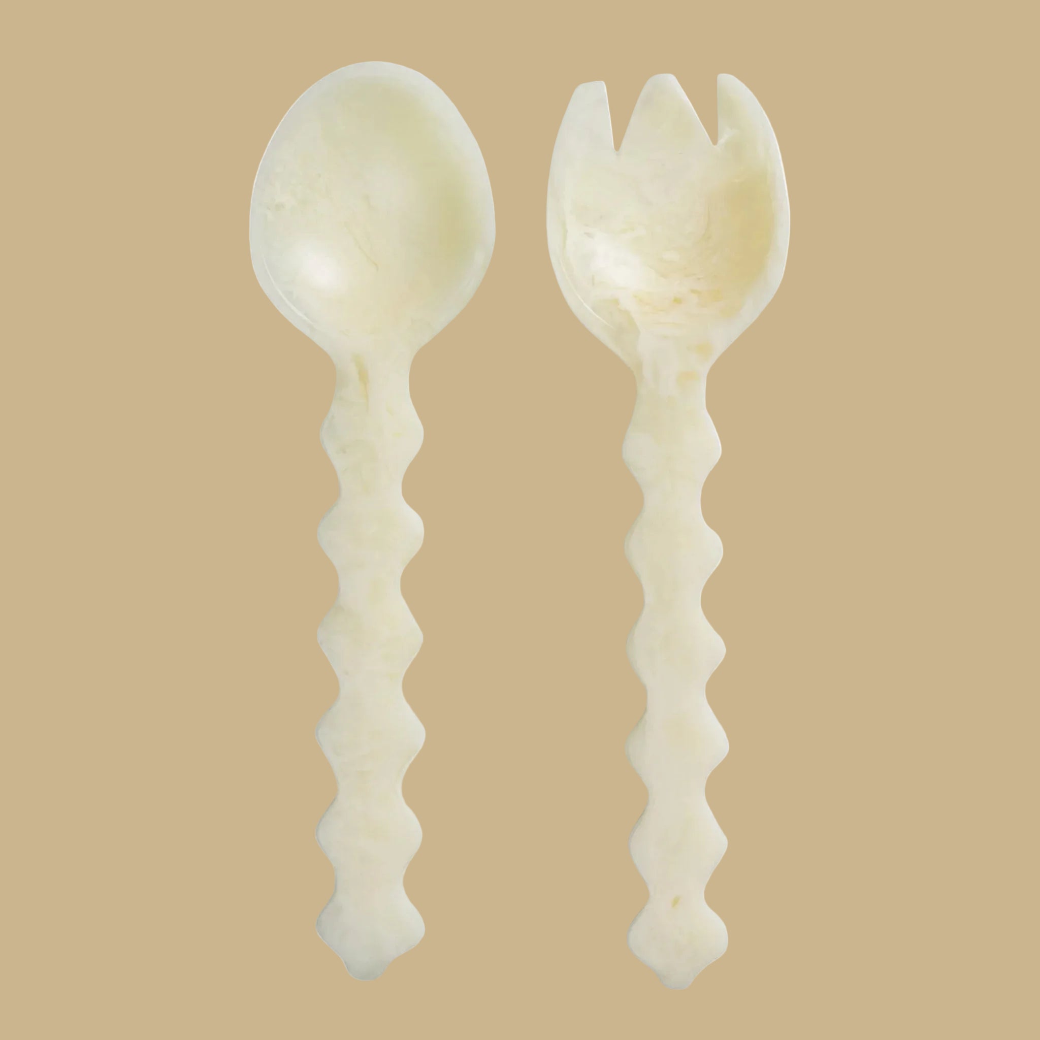 An ivory set of wavy handle salad servers. 