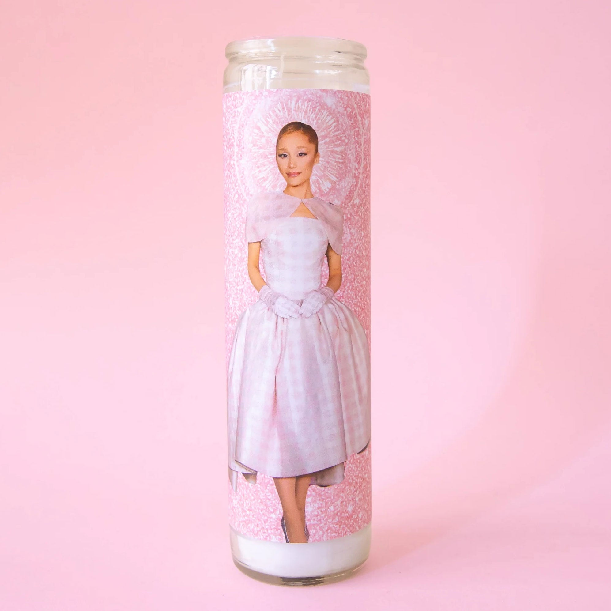 A thin pink prayer candle with a photo of Ariana Grande in a pink dress. 