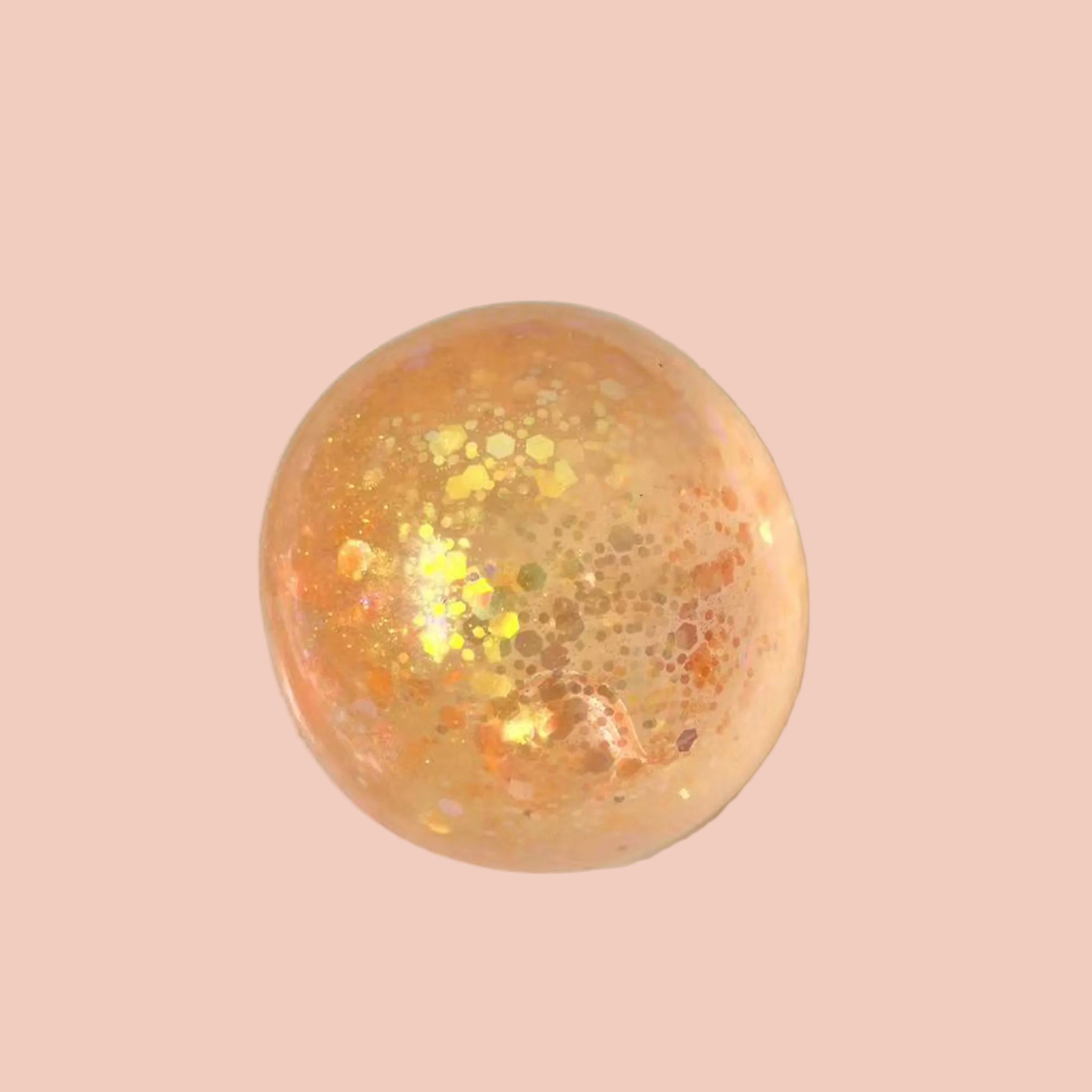 Orange bath bomb with glitter on a white plate