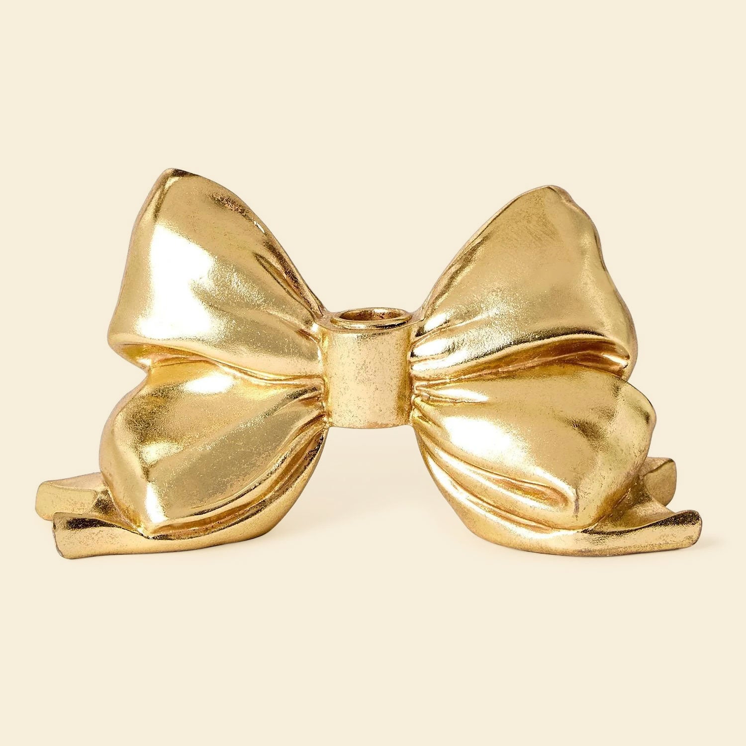 A gold bow shaped taper candle holder. 
